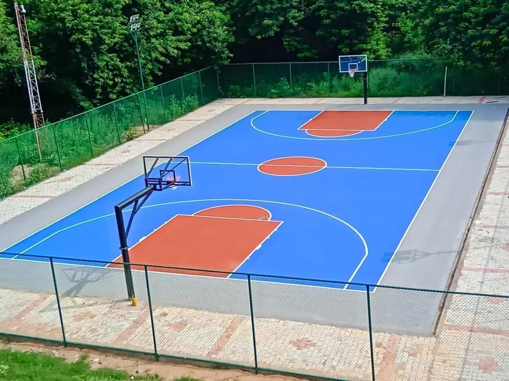 Outdoor basketball court with blue surface glass backboards and floodlights